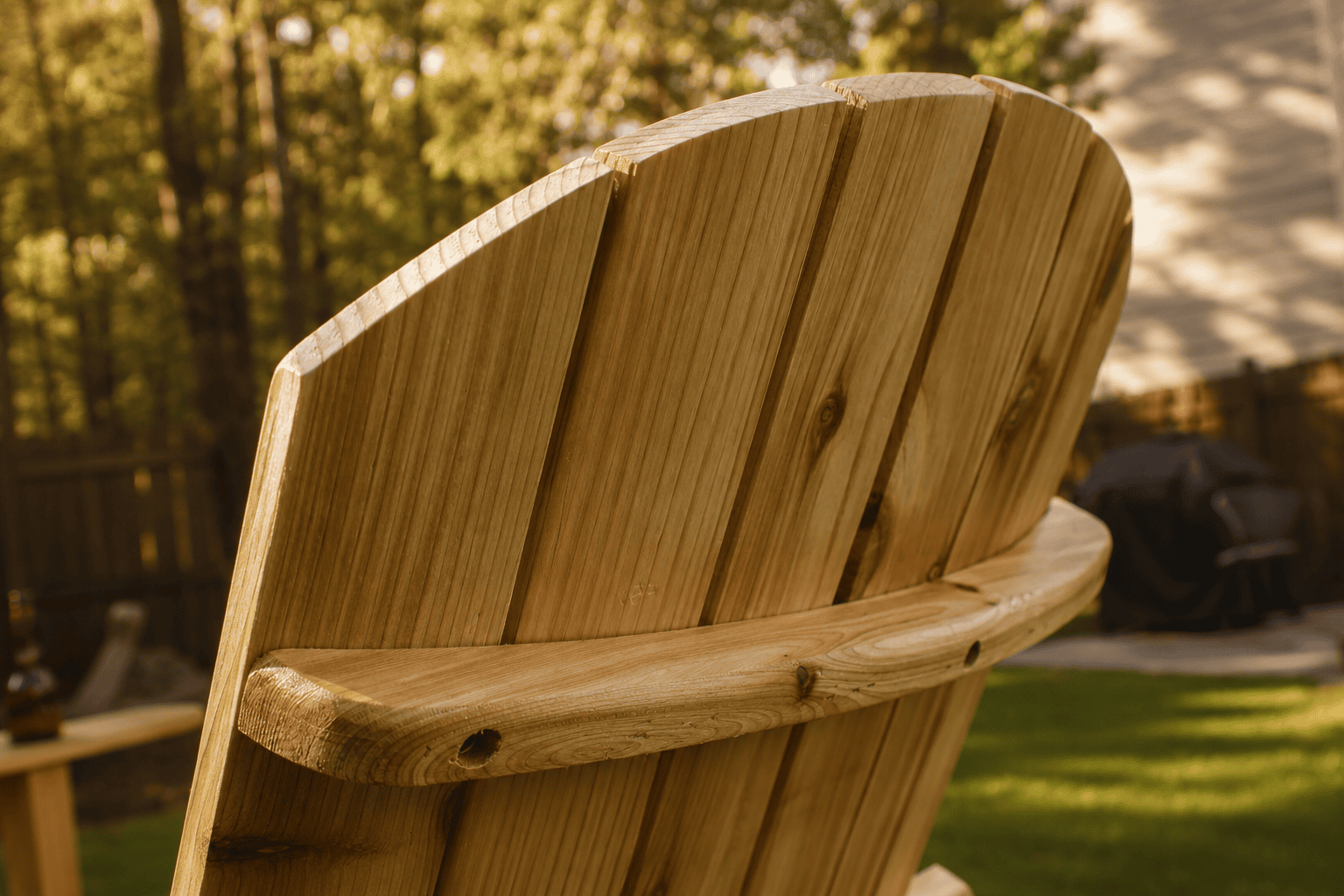 Close-up of handcrafted cedar Adirondack chair showing curved back support and wood grain