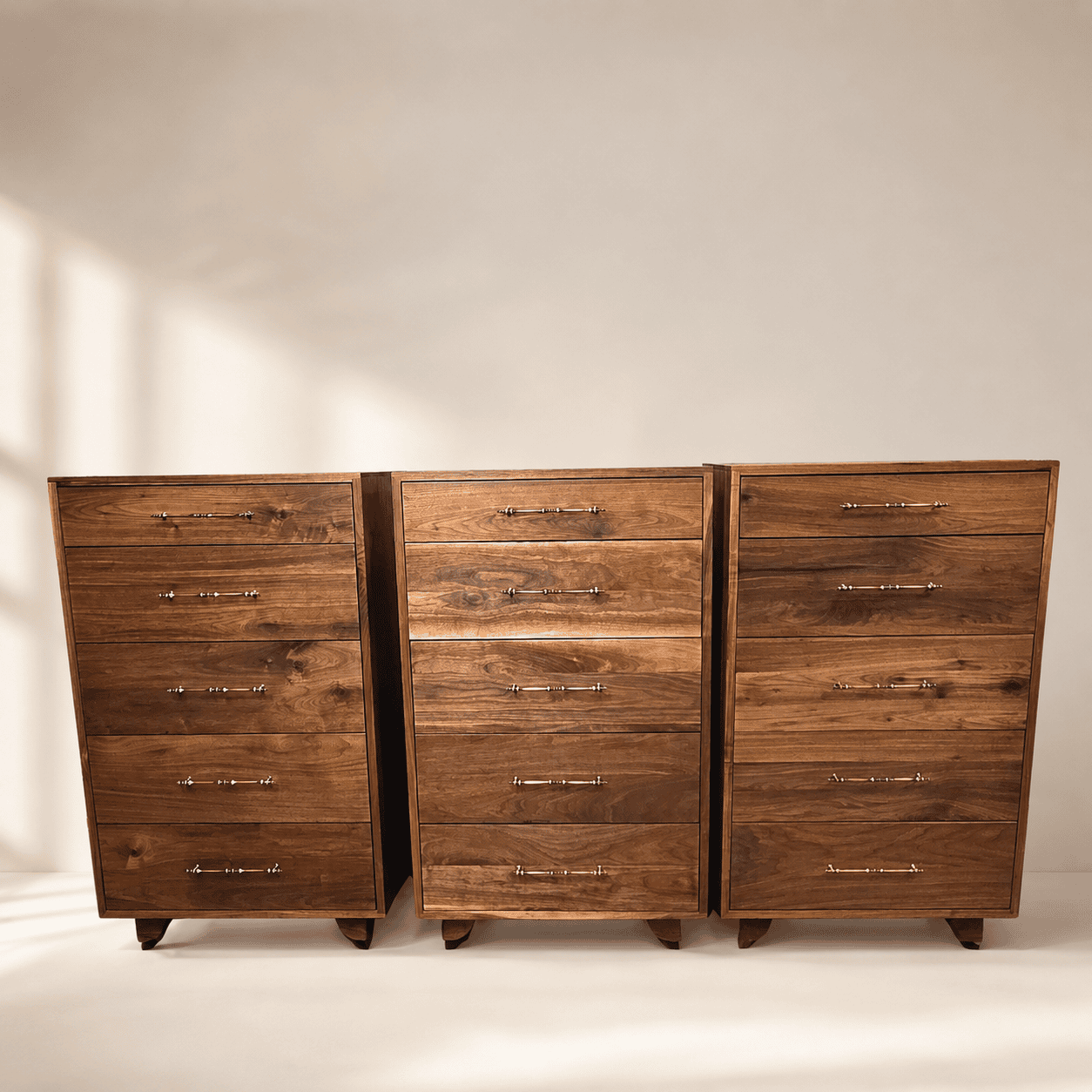 Three handcrafted solid walnut dressers with brass hardware, showcasing natural walnut grain and modern handcrafted design.