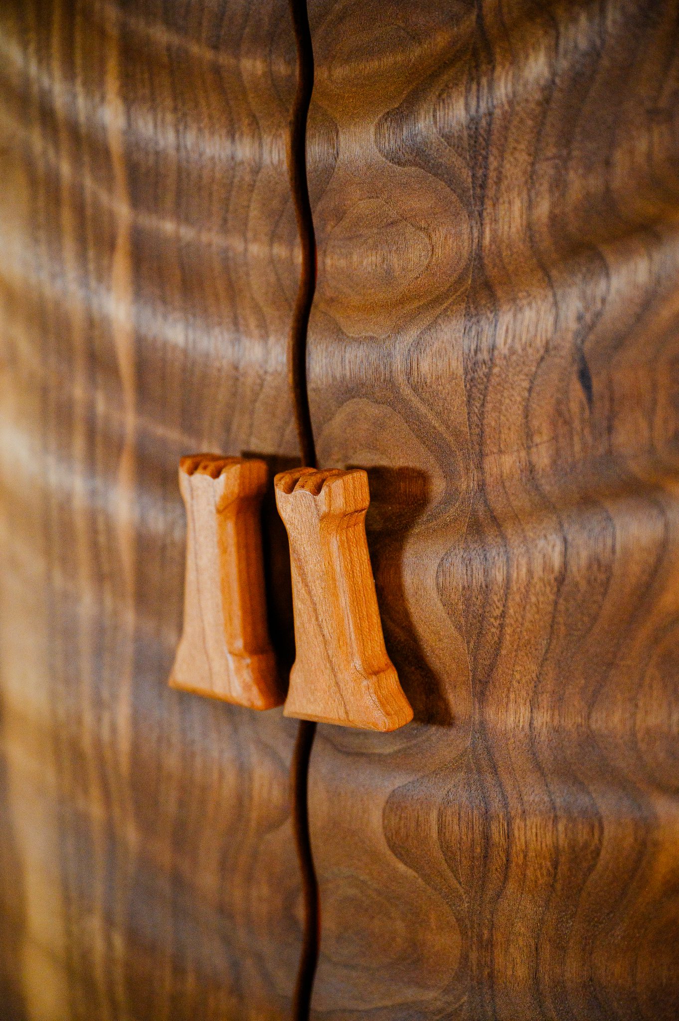 Close-up of sculpted wooden handles on handcrafted walnut chessboard